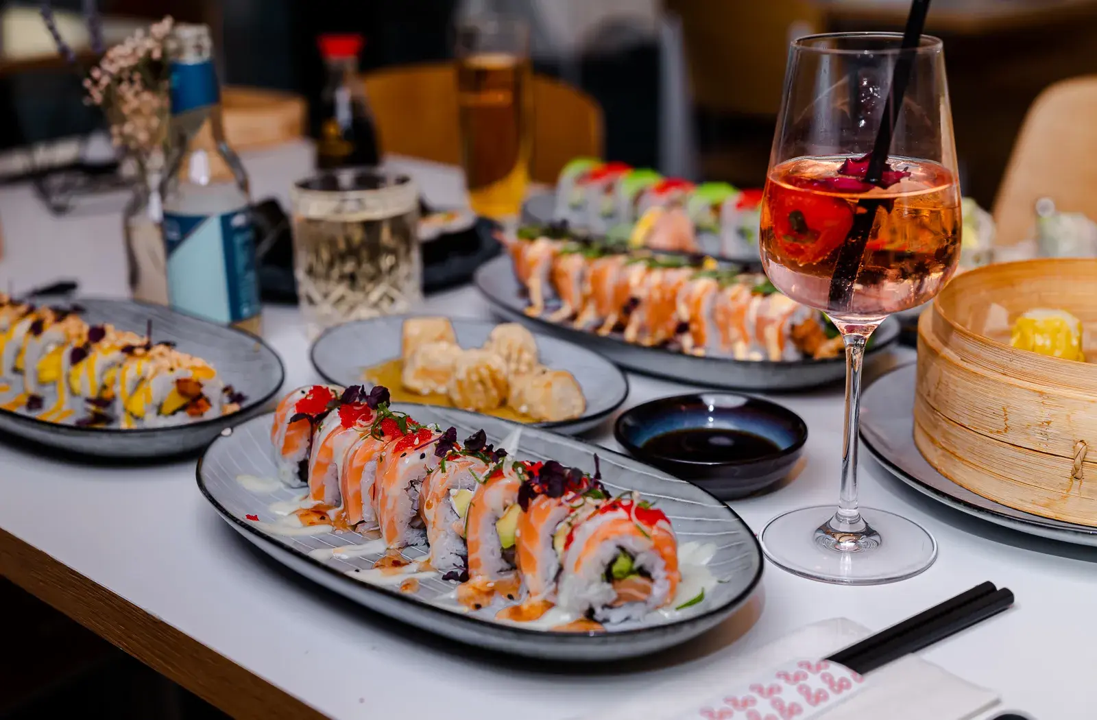 Sushi, Dim Sum und Drinks auf einem gedeckten Tisch im ra’mien go